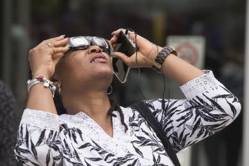 An Eclipse Party goer views the eclipse through eclipse glasses.