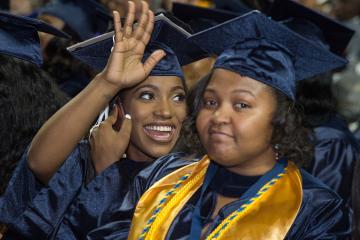 A graduate waves to family members.