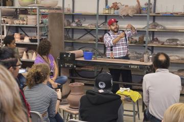 Artist Roberto Lugo speaks to the group gathered to listen and watch his demonstration