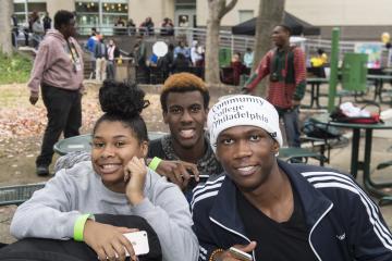 Three students smile for the camera, one wears a Community College of Philadelphia shirt tied around his head.
