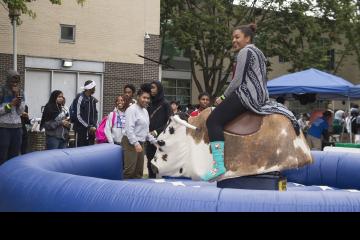 A student smiles as she rides the Mechanical Bull.