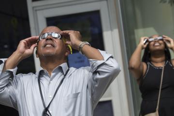 Dr. Generals, College President, views the eclipse through eclipse glasses.