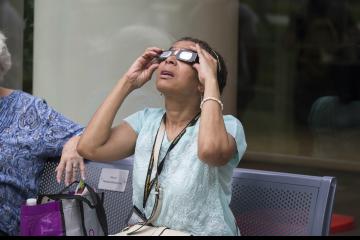 An Eclipse Party goer views the eclipse through eclipse glasses.