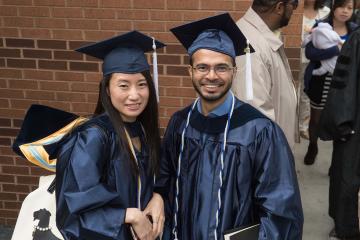 Two graduates smile for the camera.
