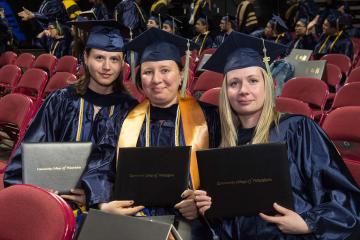 Three graduates smile for the camera.