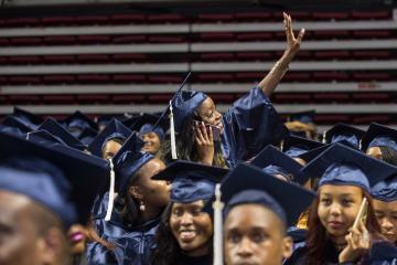 A graduate waves to her family.