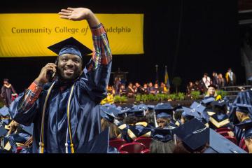 A graduate on his cell phone waves to his family.