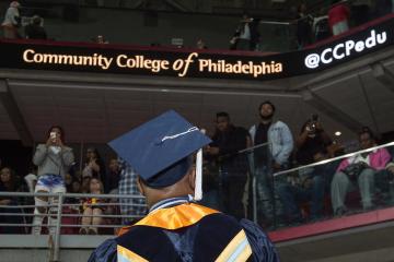 A graduate looks up at the friends and family in the arena.
