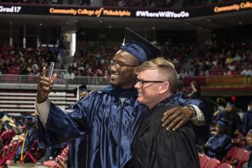 A graduate and a faculty member take a selfie together.