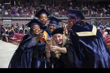 A teacher takes a group selfie with her graduating students.