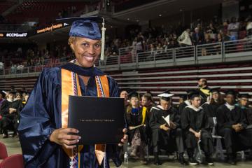 A graduate holds up her diploma.
