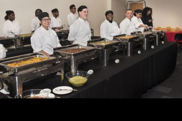 Culinary Arts students, smiling for the camera, prepare to serve a traditional Latin meal to guests.