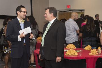 MC Nestor Torres speaks with Institutional Advancement VP, Greg Murphy at the luncheon.