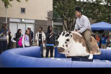 A student grins ear to ear as she rides the mechanical bull.